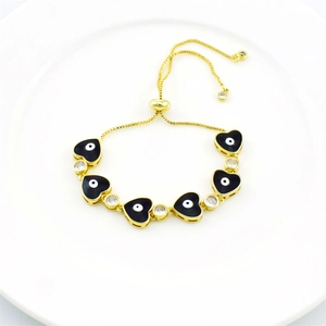 Detail of gold adjustable bracelet featuring black heart evil eye charms and clear zircons