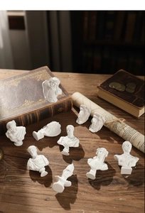 Classic resin mini gypsum busts arranged on a vintage wooden desk with old books