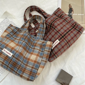 Macro shot showing blue and brown plaid wool texture and white woven label of the tote bag