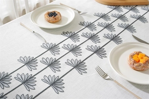 Close-up of beige waterproof tablecloth with elegant grey floral embroidery for dining decor