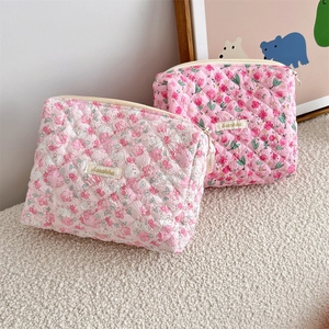 Detailed view of quilted floral makeup bags featuring high-quality zipper and woven labels
