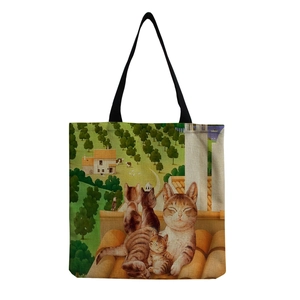 Close-up of canvas tote bag with rural landscape and cat illustration on white background