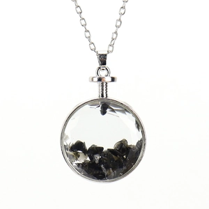 Macro shot of circular silver pendant with polished black natural stone chips