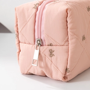 Macro shot of pink quilted cosmetic bag with bow embroidery and silver zipper