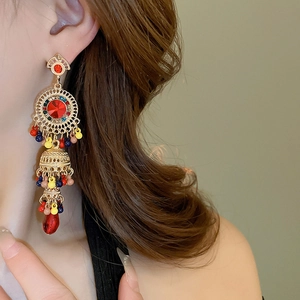 Detail of vintage gold tassel earrings with red gemstones and colorful bead accents