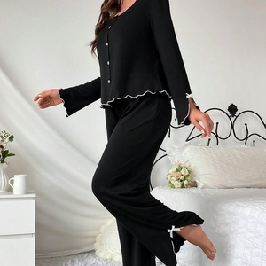 Detail of lettuce trim edges and white bow accents on black long sleeve pajama set