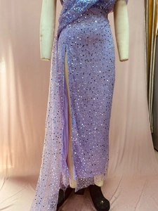 Detail of purple sequined evening dress with high slit and one-shoulder design on a mannequin