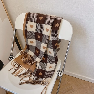 Brown and beige plaid scarf with heart patterns and fringes draped on a chair
