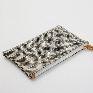 Pochette minimalista in paglia intrecciata bianca e nera con tirazip in pelle marrone