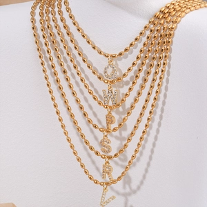 Gold beaded necklace with zircon-encrusted alphabet pendants on jewelry display