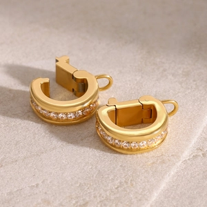 Polished gold hoop earrings with sparkling cubic zirconia on light matte surface