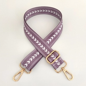 Close-up of purple nylon strap with white arrow pattern and gold metal hardware