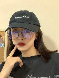 Close-up of black cotton baseball cap with white embroidery and large frame glasses