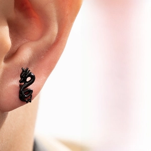 Detail of a matte black dragon stud earring worn on ear showing punk style design