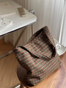 Close-up of vintage plaid wool tote bag with brown and green checked pattern on wooden table