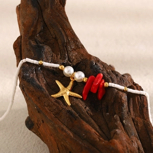 Detail of 18K gold starfish and red coral beads on a pearl beaded bracelet