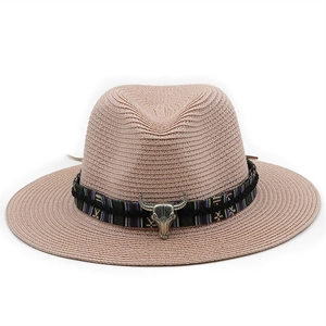Detail of pink straw fedora featuring ethnic band and metal bull head ornament