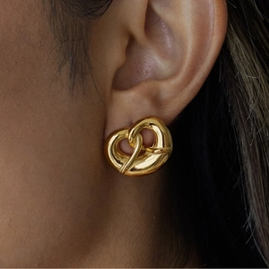 Polished 18K gold stainless steel heart-shaped pretzel earrings on a model's ear