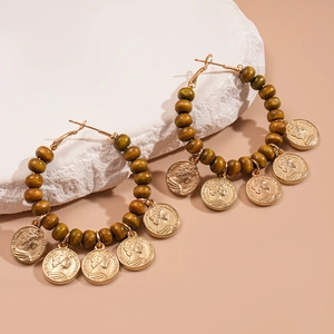 Détail de créoles en perles de bois avec pendentifs en monnaie rétro et gravures fines