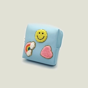 Detail of blue makeup bag with towel embroidered smiley, rainbow and heart patches