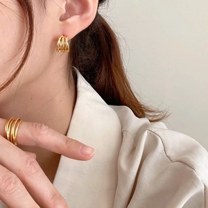 Close-up of a minimalist multi-layered golden ring and matching earrings set on a model