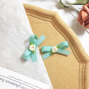 Détail de pinces à cheveux nœud bleu clair avec de petites fleurs blanches en tissu