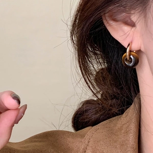 Gros plan de boucles d'oreilles créoles dorées avec pierre œil de tigre ronde