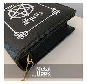 Macro shot of gold metal hook and white Book of Spells print on black lychee leather