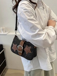 Detail of vintage gray denim shoulder bag featuring leather star patches and buckle strap