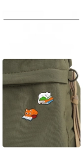 Close-up of cute cat enamel pins attached to a green canvas bag as stylish accessories