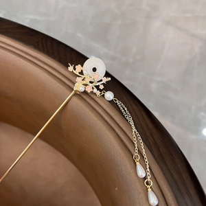 Close-up of golden hair pin with white jade disc, pink flowers and pearl tassels