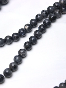 Macro detail of polished black labradorite round beads with natural blue flash sheen
