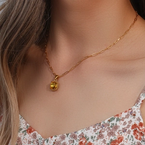 Gold paperclip chain necklace with a square yellow gemstone pendant on a female model