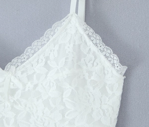 Gros plan sur la broderie florale en dentelle blanche et les fines bretelles de la robe