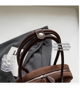 Close-up of premium brown suede bag featuring durable leather handles and silver hardware