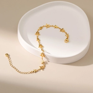 Star-shaped 18K gold plated bracelet with adjustable chain on a decorative ceramic tray
