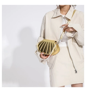 Detailansicht der goldenen Muschelhandtasche mit Perlengriff und Leder-Schultergurt