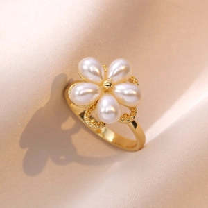 Elegant gold ring featuring a delicate five-petal pearl flower on a pink fabric background