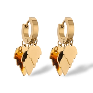 Macro detail of high-polish gold-plated stainless steel leaf drop earrings on white background