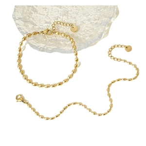 Minimalist gold oval bead bracelet in stainless steel on a textured glass display
