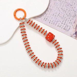 Macro shot of orange crystal rhinestones on a stylish phone charm with luxury dice detail