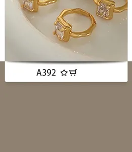 Macro detail of gold wavy rings with square clear zircon on a white reflective tray