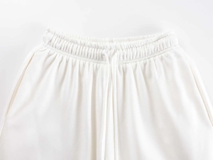 Detail of high waist white knit sweatpants featuring elastic waistband and matching drawstring
