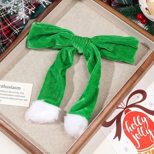 Green velvet Christmas bow hair accessory with white pom-poms on a festive background
