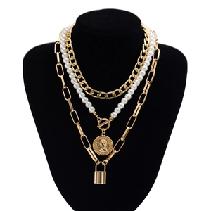 Detailed view of layered baroque pearl necklace with golden coin and lock pendants