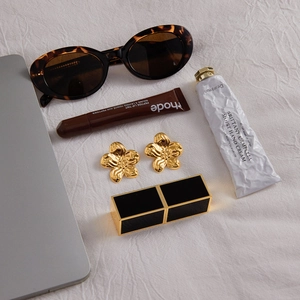 Detail-Flachbild von 18K Gold Blumenohrringen mit Lippenstift und Trend-Accessoires
