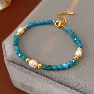 Detail of blue crystal and baroque pearl bracelet with gold lobster clasp on velvet