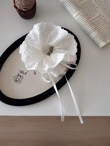 Detailed view of white floral lace scrunchie with elegant satin drawstring ribbons