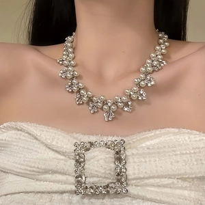 Detailed close-up of a floral pearl necklace with rhinestones on a female model