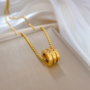 Detail of a gold titanium steel necklace featuring a three-ring cylindrical pendant on silk